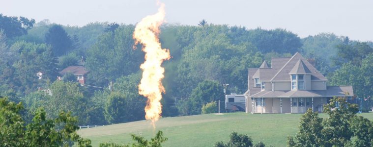 A flare from a fracking well burns off excess gas near a home.