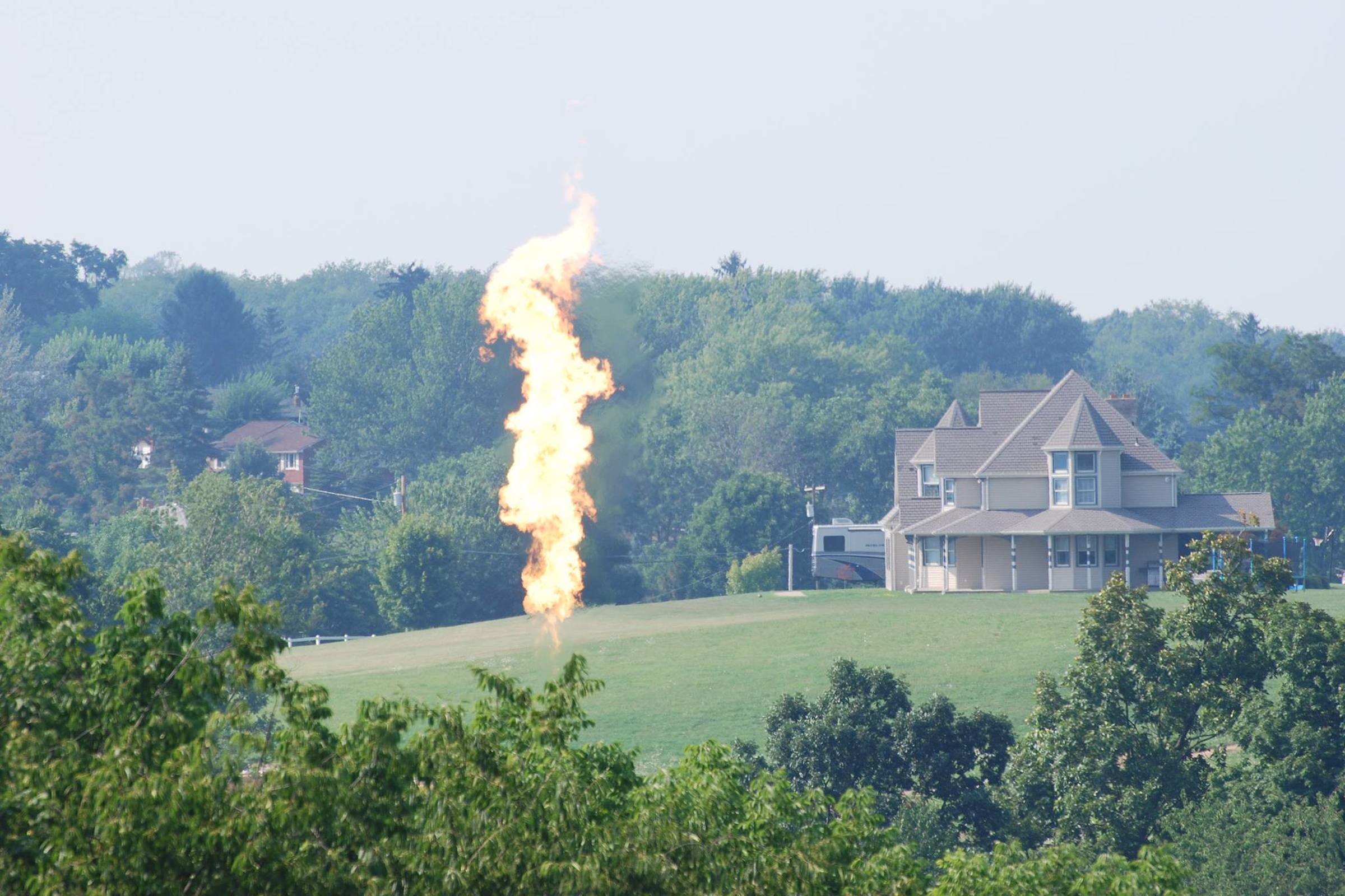 A flare from a fracking well burns off excess gas near a home.