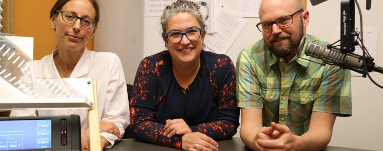 Three people sit in a radio studio.