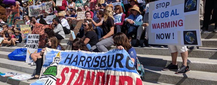 Climate Change Protestors on the steps of the state capitol with a sign that reads," Harrisburg Stand Uo."