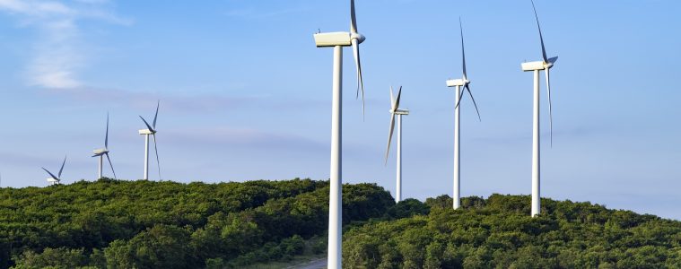 Wind turbines in a row on a green hilltop