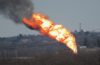 A massive tower of flames with black smoke as seen from afar