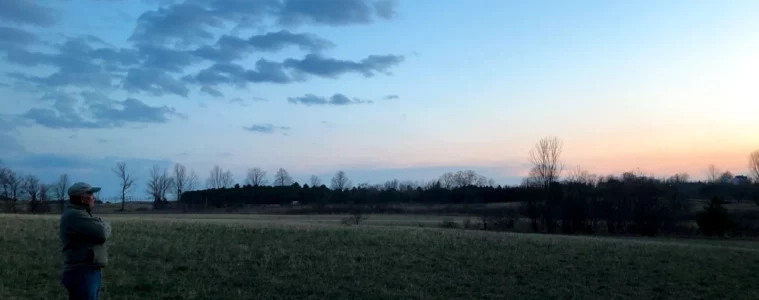 Brian Granger stands at the edge of a field at dusk