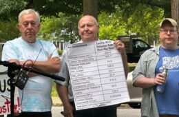 Three men hold signs about air pollution