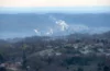 landscape shot of emissions rising from smoke stakes in the distance over a valley