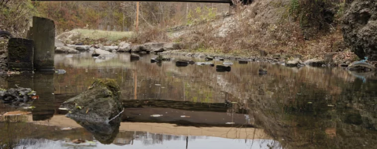 A stream with a rocky embankment with a concrete bridge over it