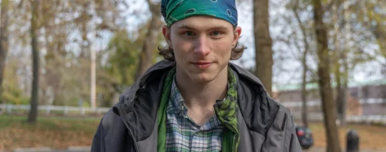 A young man in a green standing bandana outside