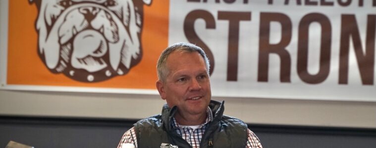 Alan Shaw sits in front of a banner that reads "East Palestine Strong."