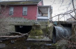 A stream goes under a house through a large culvert