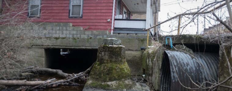 A stream goes under a house through a large culvert