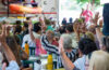 People are seated at tables, some with their hands raised.