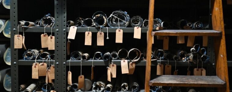 Rolls of maps with hand written tags hanging over shelves.