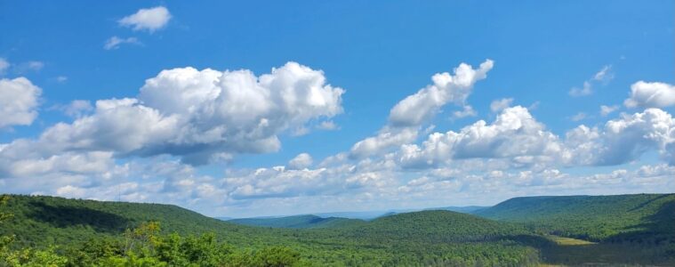 Rolling hills under a blue sky with white puffy clouds