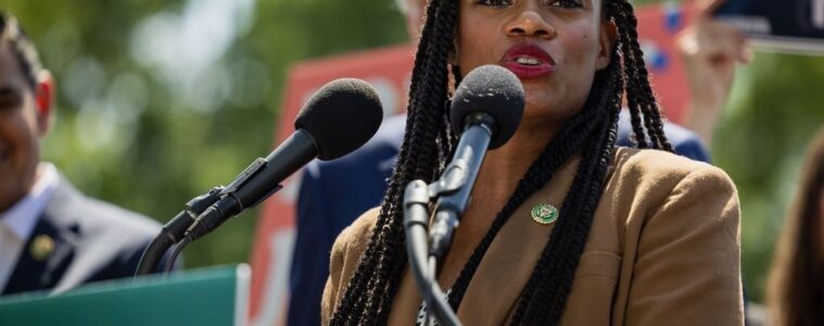 Summer Lee speaks into microphones at a podium outside.