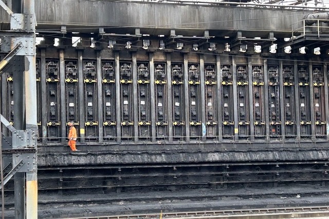 A massive industrial thing with a workers standing next to it