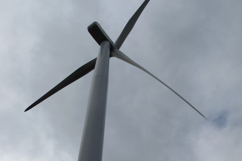 A wind turbine from below against a dark gray, cloudy sky