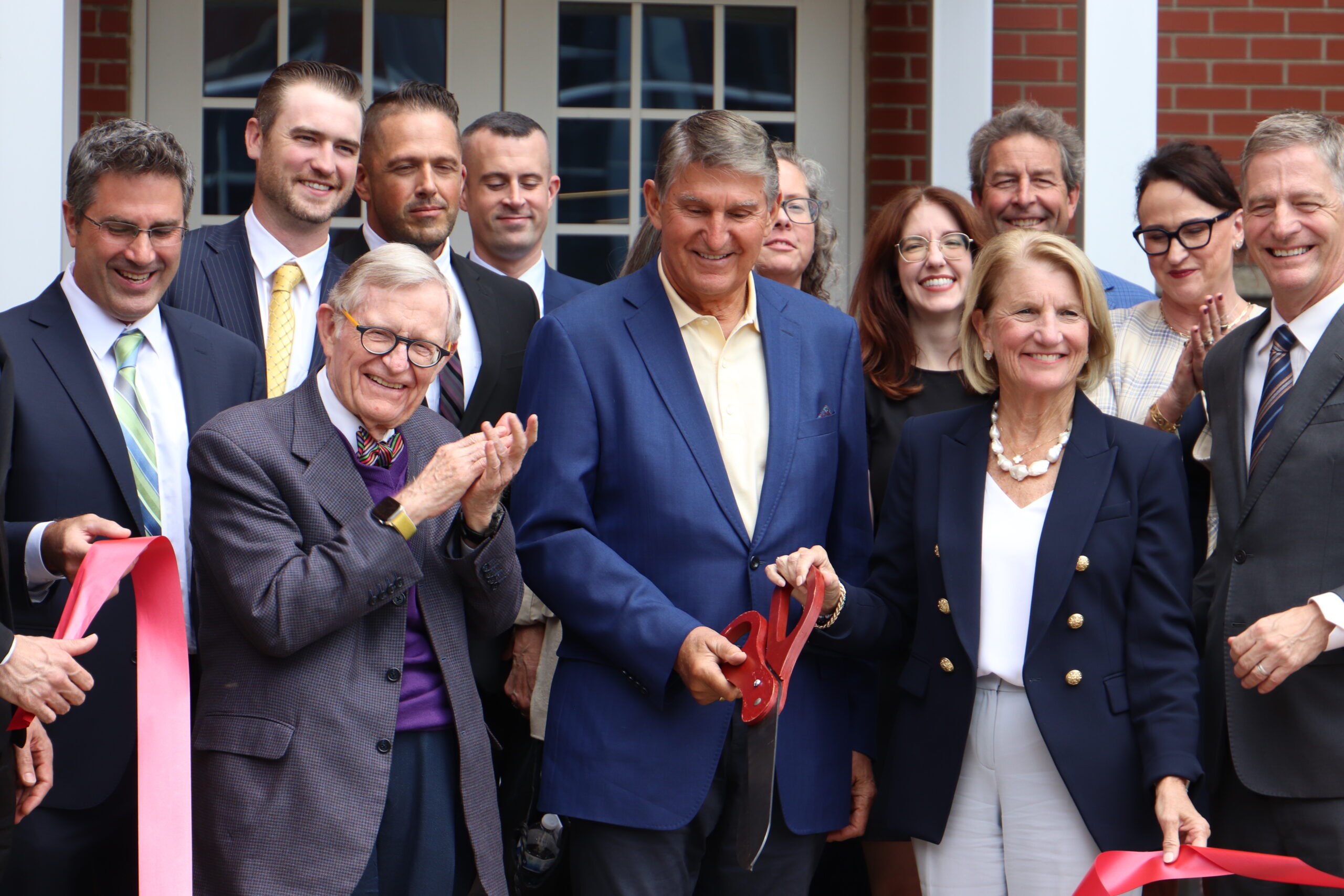 A group of people dressed in business attire stand in front of a building.