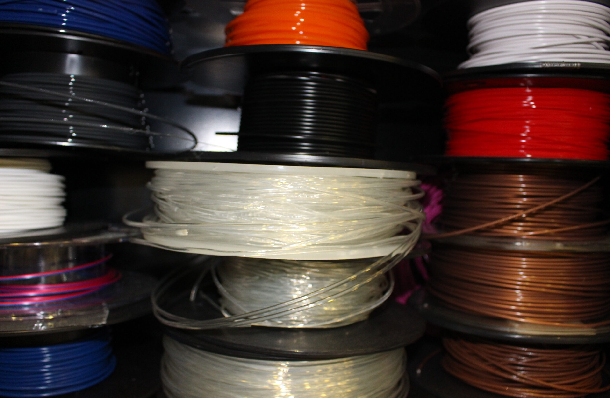 Spools of red, white and black recycled plastic coil stacked on top of one another.