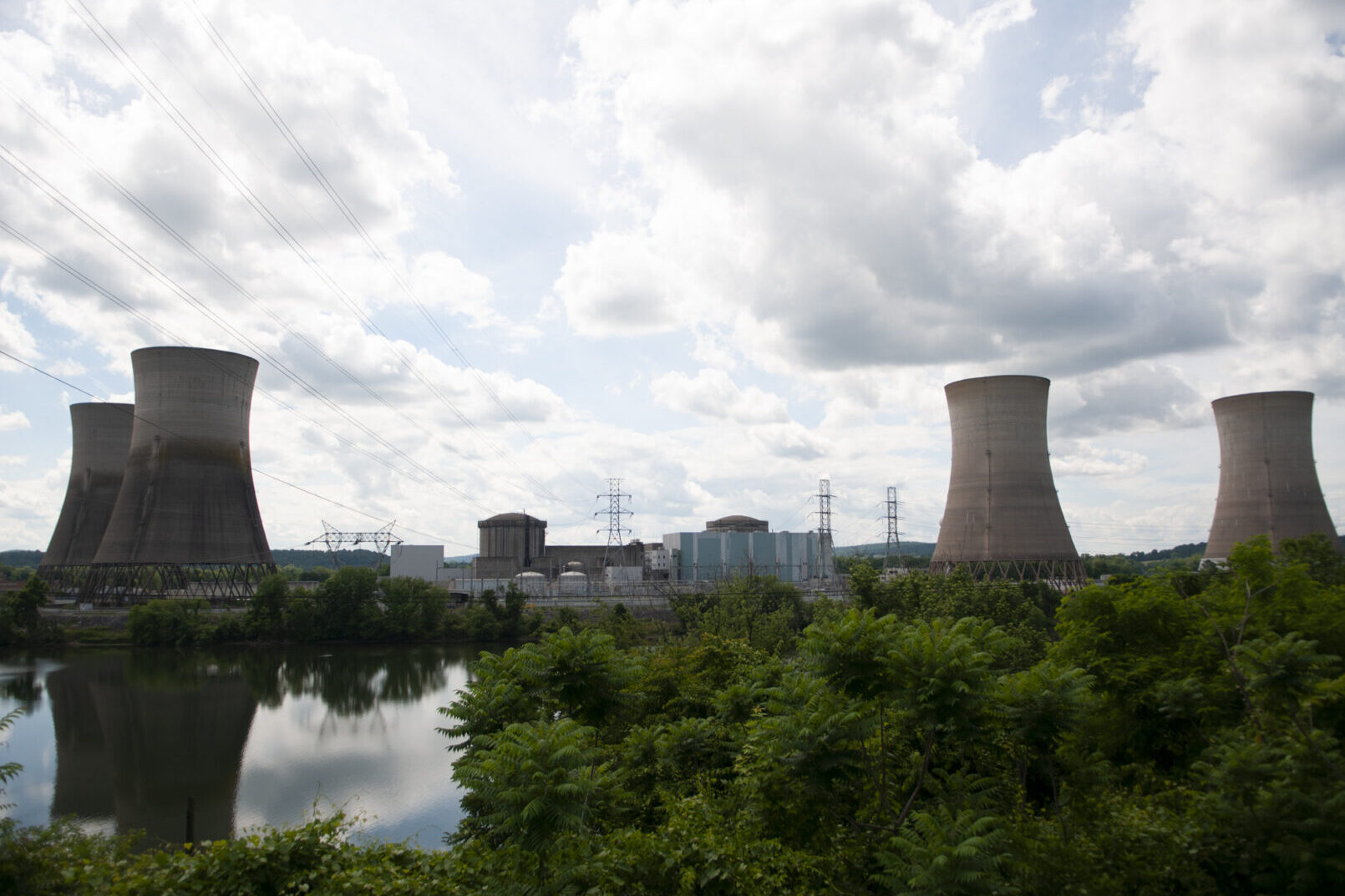 Four gray towers with water and greenery in front.