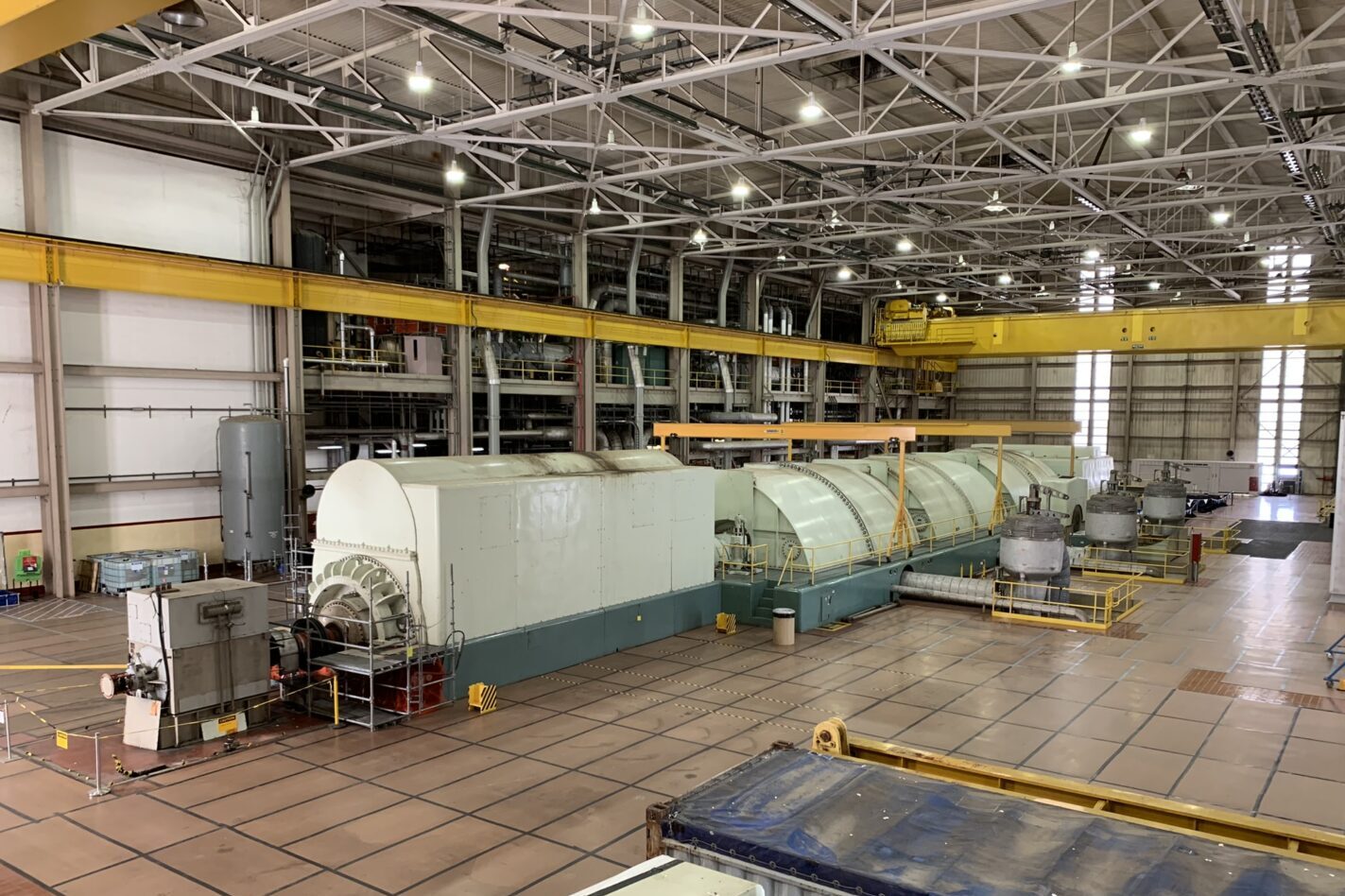 Cylinder-shaped white turbines in an industrial room with metal scaffolding