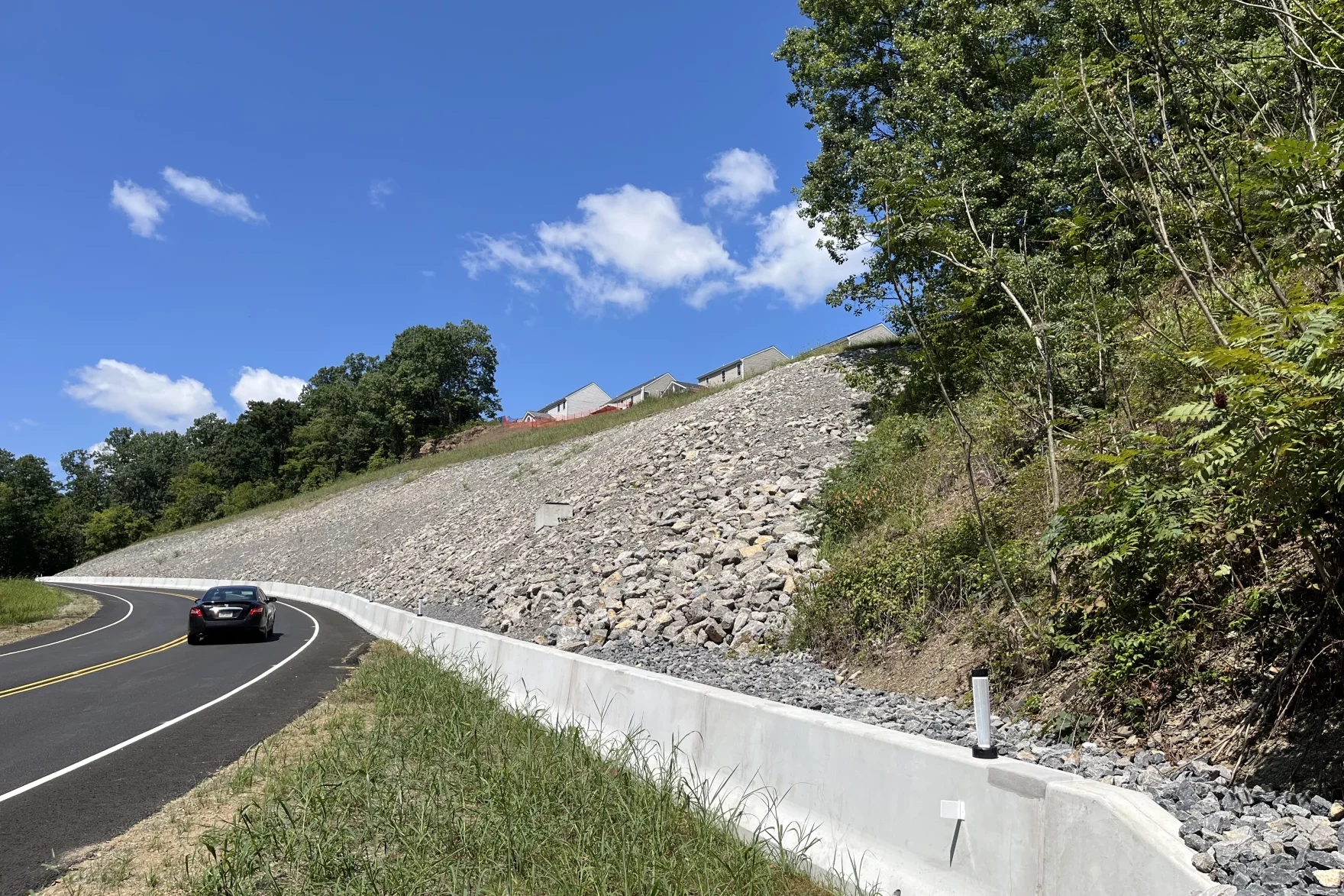 A steep hillside is covered with rocks along the side of a road.