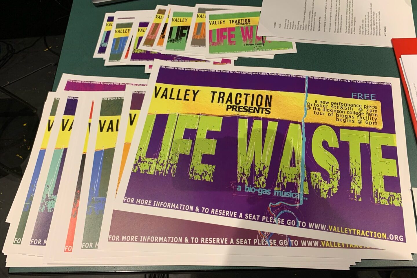 Signs and fliers for the 'Life Waste' musical on a table