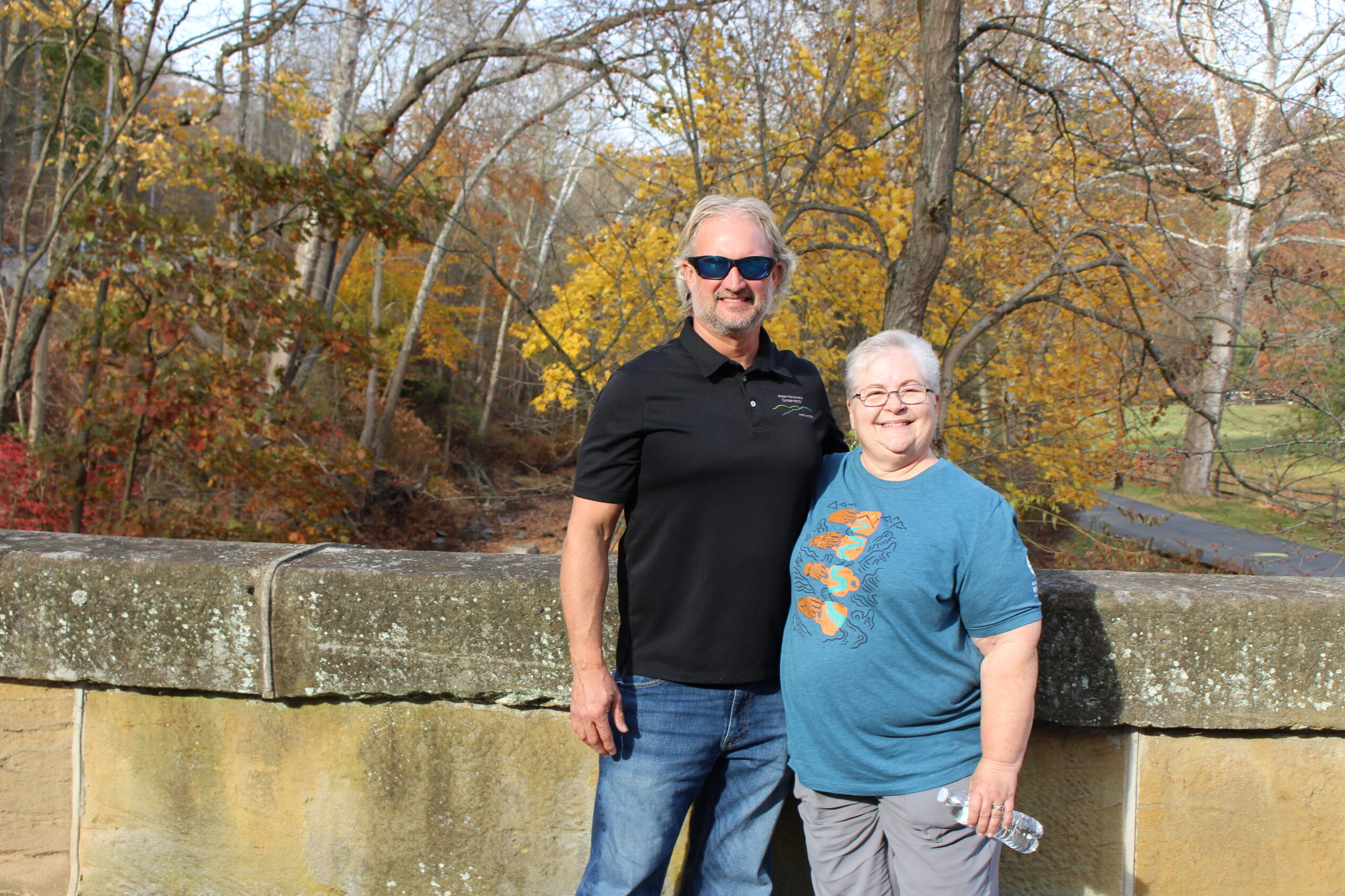 Two people stand on a bridge over Little Sewickley Creek