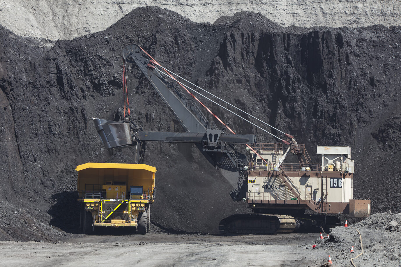 A truck loads coal from a large pile