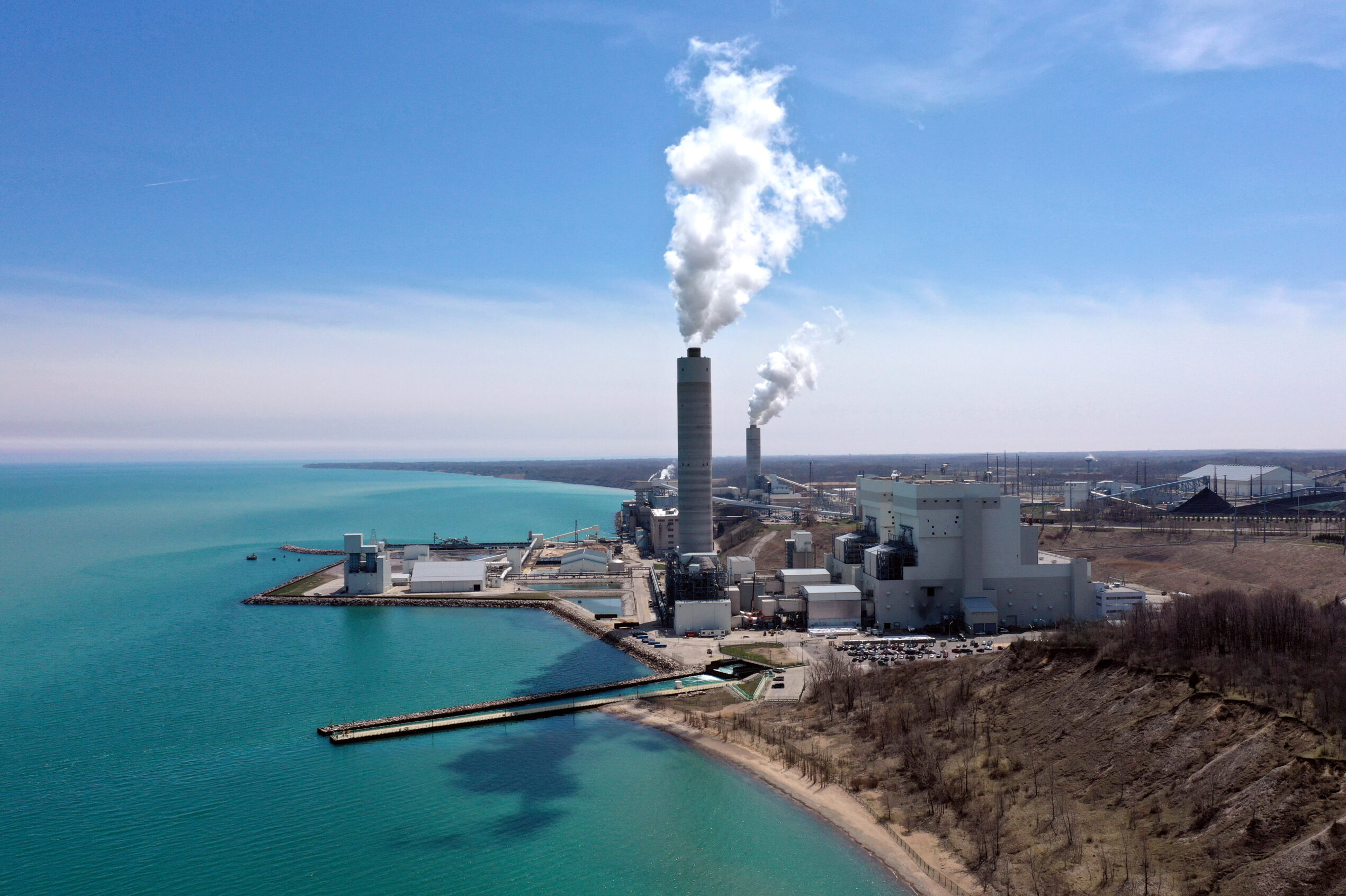 A smokestack along water against a blue sky