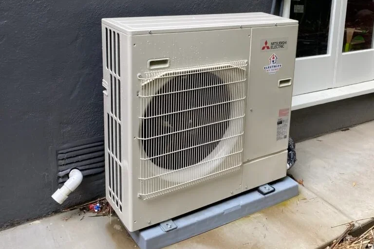 A slim square appliance with a large opening for a fan sits next to a wall.