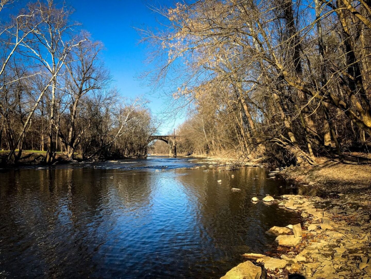 A river waterway with an arched bridge in the distance